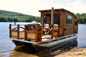 Small wooden houseboat with a cabin and a deck on a lake