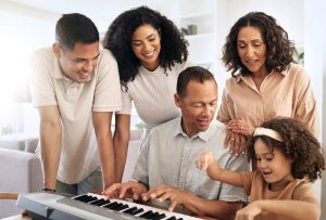 Family gathered around a keyboard, playing together