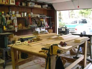 Garage shop with an open door, a long workbench and loaded shelves