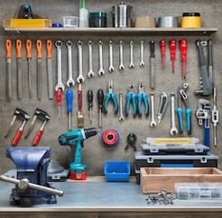 Pegboard tool wall with wrenches, pliers, clamps and a bench vise